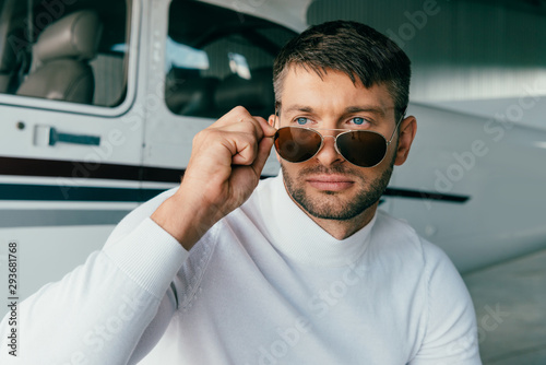 pensive man in sunglasses looking away near plane