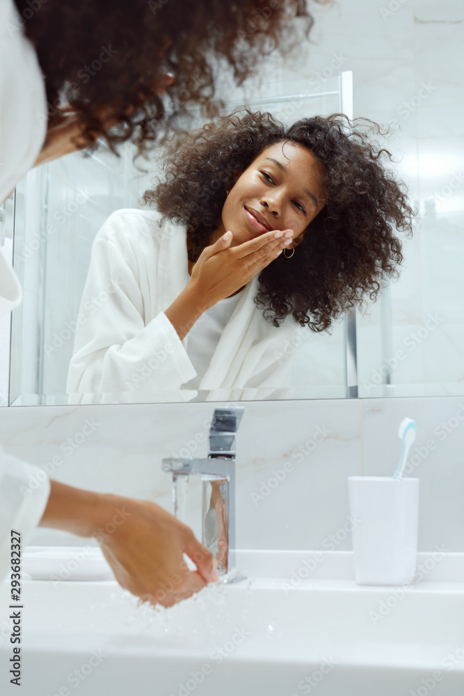Skin care. Woman washing face with water in sink at bathroom Skin care. Woman washing face with water in sink at bathroom