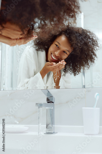 Skin care. Woman washing face with water in sink at bathroom