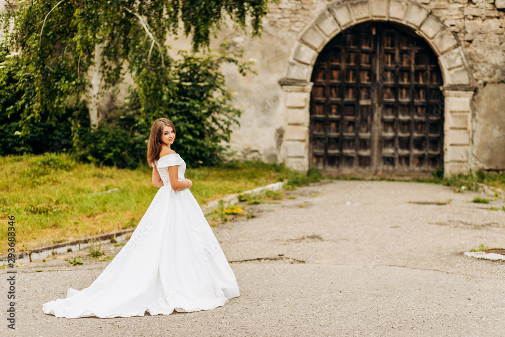 A dreamy bride in a lush dress swirls near the castle