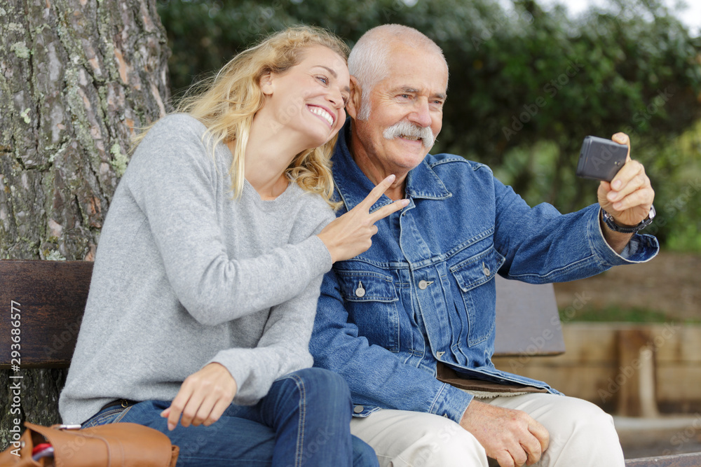 happy smiling young daughter and senior dad with smartphone happy smiling young daughter and senior dad with smartphone