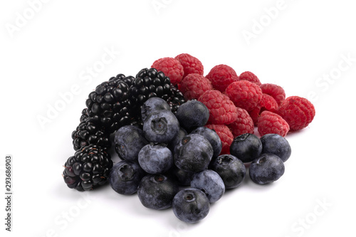 on a white background, ripe and healthy berries of red raspberry, dark violet blackberry and blueberry are gathered together