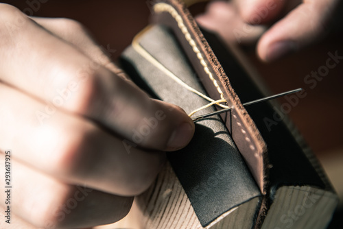 a tanner in a workshop makes a wallet from genuine leather in a special clip