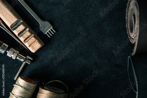 background of black genuine leather with leather tools with brown tinting