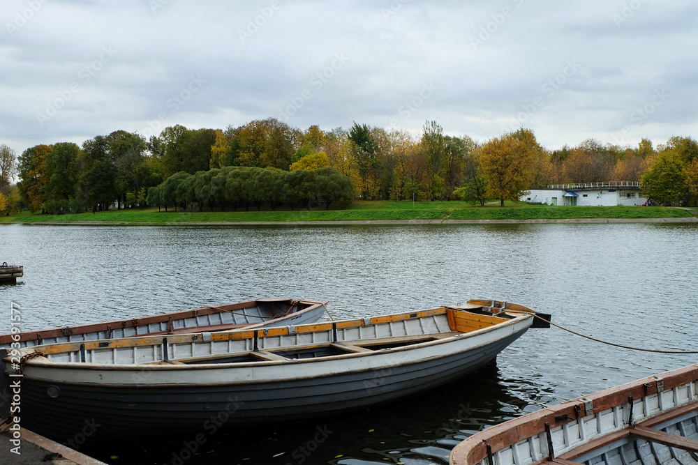 Autumn landscape: a pond with an island, a pier and boats in the park.
