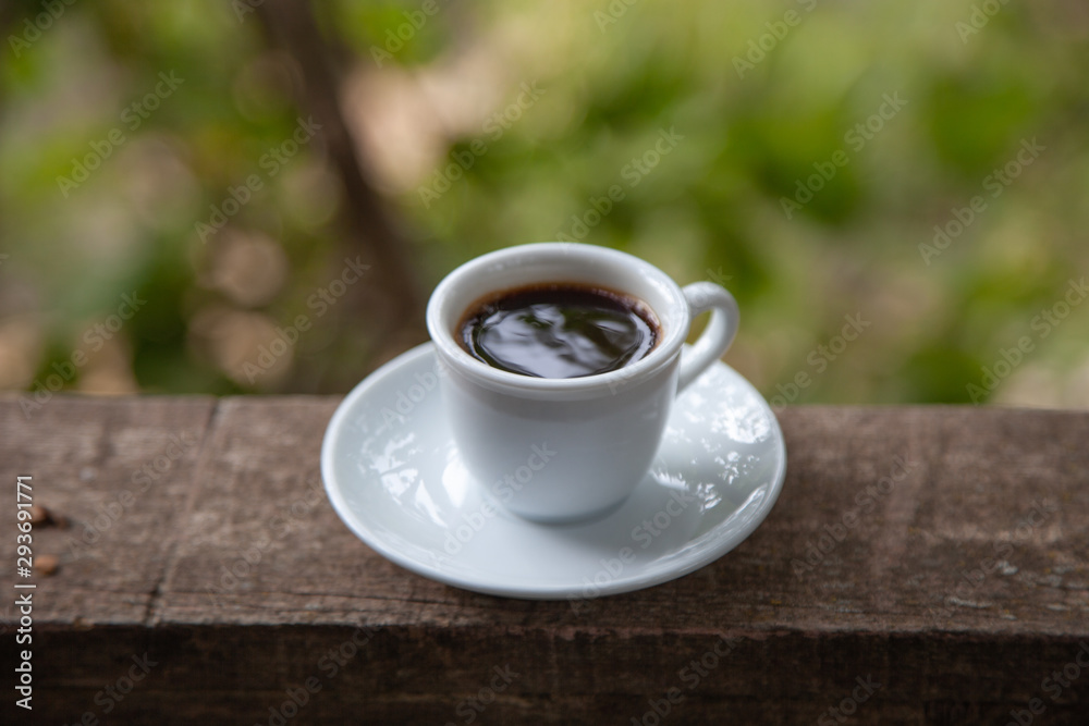 Black coffee in white cup on the edge of a village house balcony with natural background Black coffee in white cup on the edge of a village house balcony with natural background