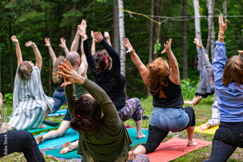 Diverse people enjoy spiritual gathering A group of people of all age groups are seen in warrior I pose (virabhadrasana I), during an outdoor yoga session as part of a multicultural celebration. © Valmedia