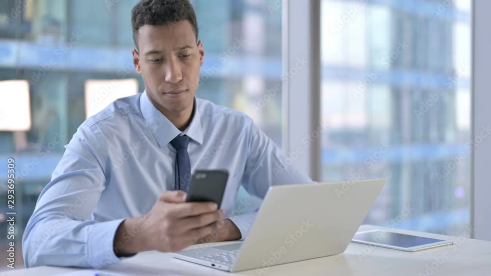 African American Businessman using Cellphone in Office African American Businessman using Cellphone in Office