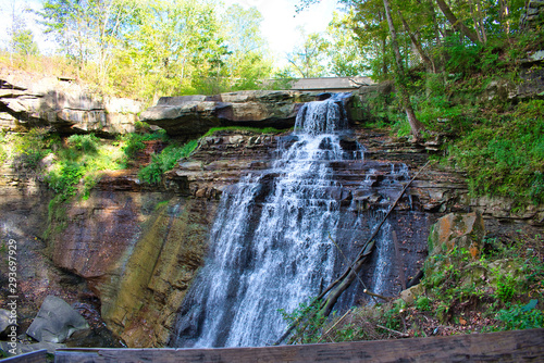 Brandywine Falls at Cuyahoga Valley National Park. Blue water rushing over colorful rocks on a sunny day. Isolated in forest.
