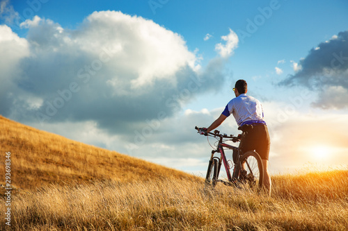 Back view of a man with a bicycle at mountain