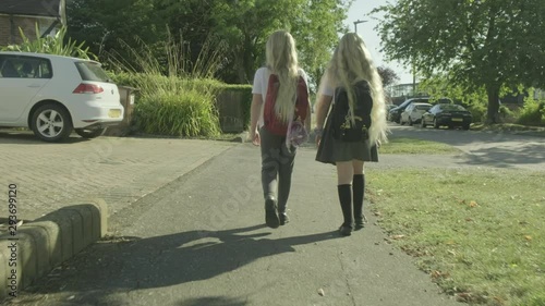 Pre teen twin caucasian girls walking to school