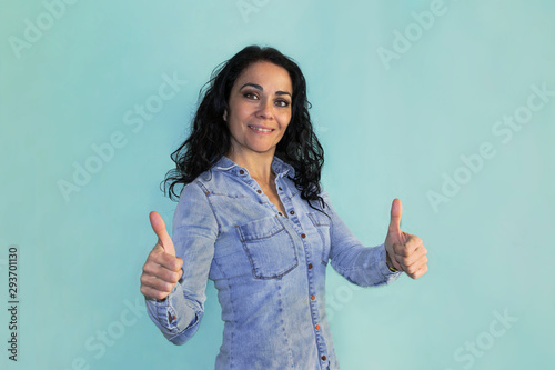 Brunette woman over isolated background doing happy thumbs up gesture with hands