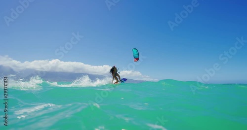 Young active woman riding by smiling kitesurfing in the ocean on a sunny day, fun times doing extreme sports
