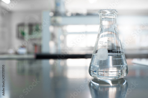 single glass flask with water in chemistry education laboratory background
