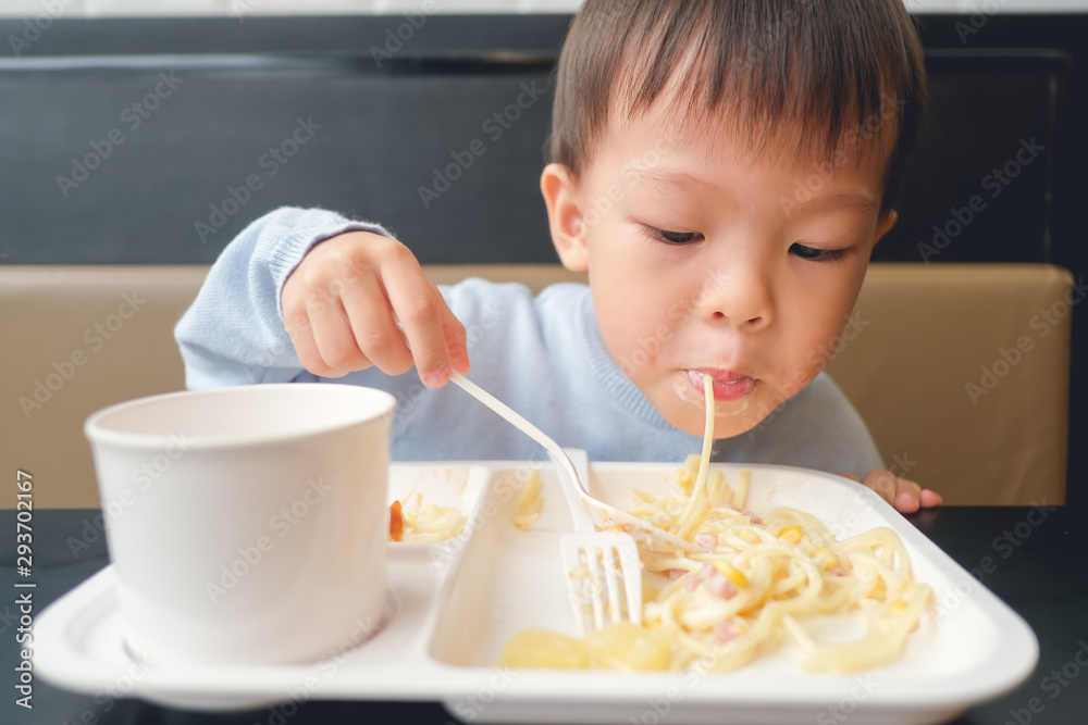 Cute little Asian 3 - 4 years old toddler boy toddler boy child eating spaghetti with spoon and fork for lunch at home, in restaurant, Yummy toddler food, Self feeding concept, Soft & Selective focus Cute little Asian 3 - 4 years old toddler boy toddler boy child eating spaghetti with spoon and fork for lunch at home, in restaurant, Yummy toddler food, Self feeding concept, Soft & Selective focus