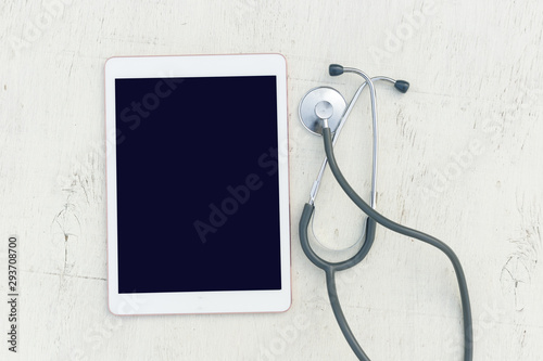 Stethoscope and tablet on a light grunge background. The concept of technology and medicine, distant treatment, health. Top view image. Copy space for text.