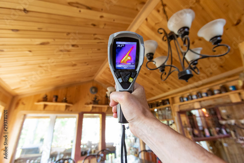 Indoor damp & air quality (IAQ) testing. A point of view perspective of an indoor environmental quality assessor at work, using a spot thermovision device to examine a wood cladding ceiling.