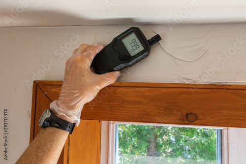 Indoor damp & air quality (IAQ) testing. A close up view of an indoor environmental quality assessor using a handheld digital device with lcd numeric display during a residential dwelling check up.