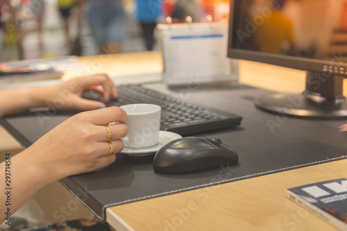 Woman hand holdding coffee cup with working table