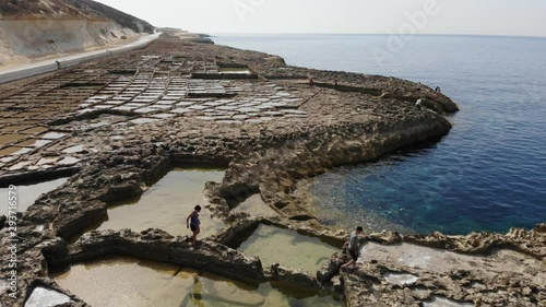 An aerial drone shot as people walk among the rock Salt Pans on Gozo Island in Malta. photo