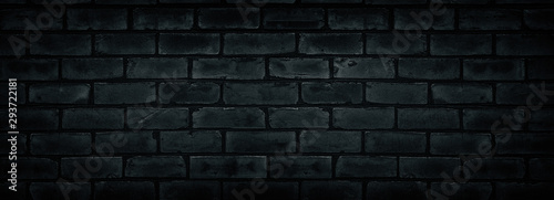 Old shabby black brick wall texture. Cement block dark widescreen backdrop. Gloomy grunge wide background