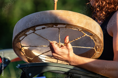 Sacred drums during spiritual singing. A close up view on the hands of a drummer playing a traditional handcrafted native drum on a sunny day in a public park as people celebrate culture. photo