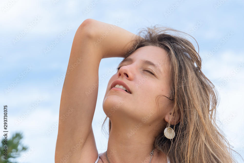 Young woman outdoors with eyes closed holding her hair