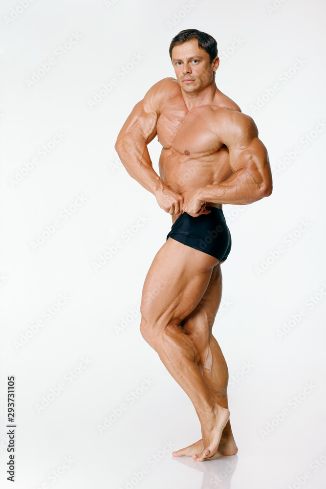Athlete bodybuilder biceps arms. Turned to the camera with its left side. The arm is bent at the elbow and clenched into a fist, biceps in tension. The leg is bent at the knee, leg muscles are visible Athlete bodybuilder biceps arms. Turned to the camera with its left side. The arm is bent at the elbow and clenched into a fist, biceps in tension. The leg is bent at the knee, leg muscles are visible