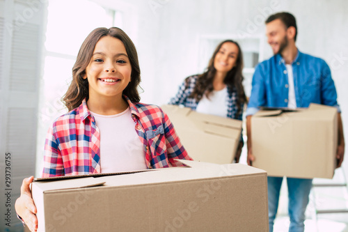 Sheer excitement. A little girl with chestnut hair is genuinely excited about helping her parents unpack the boxes to furnish a new home faster.