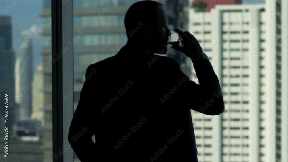 Young businessman drinking and admire view from window at office