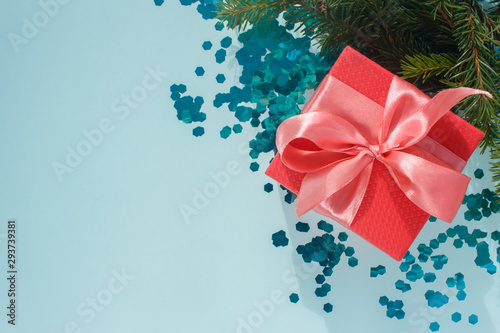 New Year Christmas Xmas 2020 holiday celebration red present gift box with satin pink bow, fir tree branch, glittering confetti, copy space on turquoise background. Flat lay minimal style. 