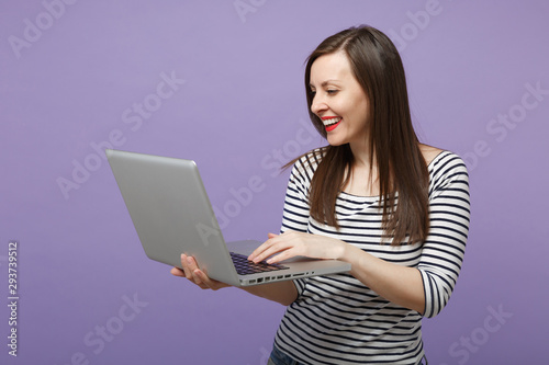 Young brunette woman girl in casual striped clothes posing isolated on violet purple background studio portrait. People sincere emotions lifestyle concept. Mock up copy space. Hold tablet pc computer.