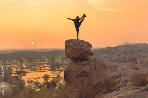 An Acrobat performs acrobatics at the spectacular sunset point at Hampi in Karnataka  India. Acro yoga   bouldering and music performers enjoy daily sunset here. Gymnasts outdoor
