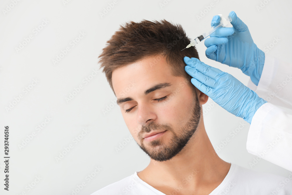 Man with hair loss problem receiving injection on grey background Man with hair loss problem receiving injection on grey background