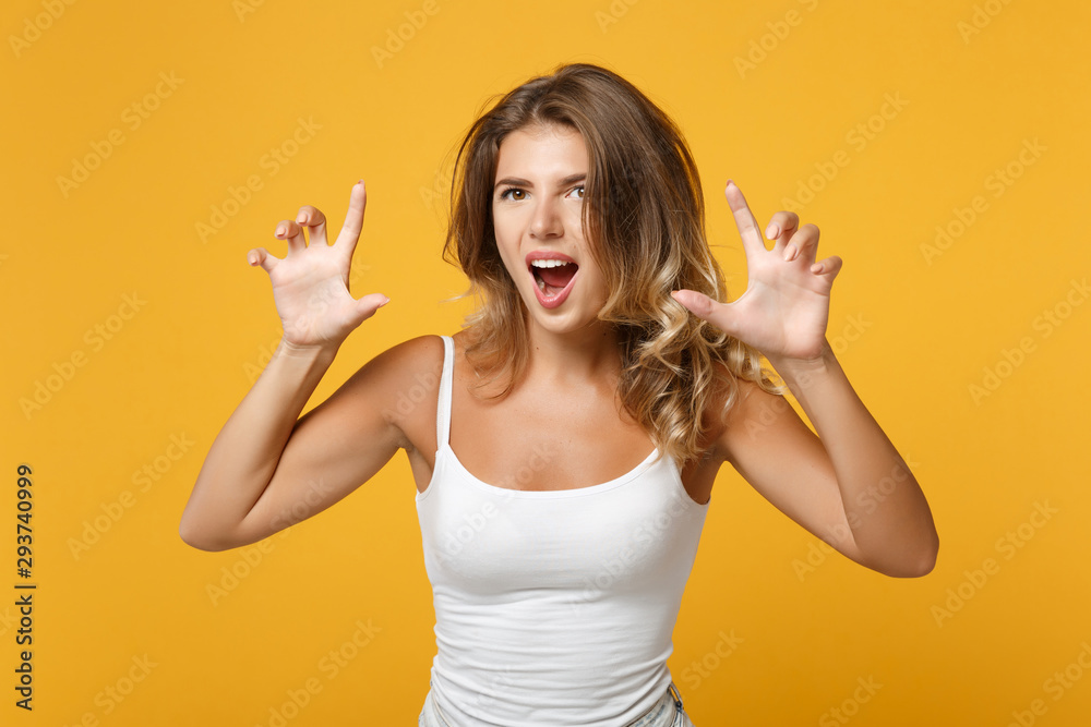 Young woman in light casual clothes posing isolated on yellow orange background studio portrait. People lifestyle concept. Mock up copy space. Shouting, growling like animal, making cat claws gesture. Young woman in light casual clothes posing isolated on yellow orange background studio portrait. People lifestyle concept. Mock up copy space. Shouting, growling like animal, making cat claws gesture.
