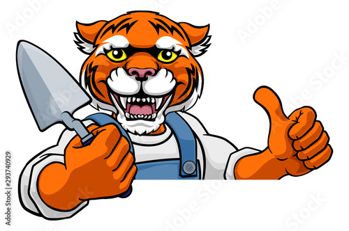 Fototapeta Naklejka Na Ścianę i Meble -  A tiger bricklayer builder construction worker mascot cartoon character holding a trowel tool and peeking around a sign and giving a thumbs up