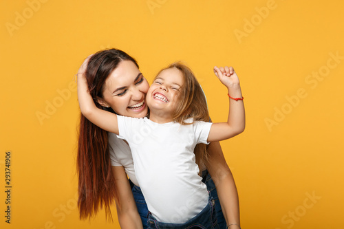 Woman in light clothes have fun with cute child baby girl 4-5 years old. Mommy little kid daughter isolated on yellow background studio portrait. Mother's Day love family parenthood childhood concept. photo