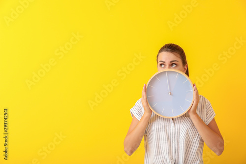 Beautiful young woman with clock on color background
