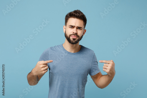 Young perplexed unconfident man in casual clothes posing isolated on blue background, studio portrait. People sincere emotions lifestyle concept. Mock up copy space. Pointing index fingers on himself.