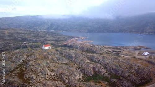 Aerial, tracking, drone shot, overlooking a house on a hill, the Lagoa Comprida lake and the Maques da silva dam, in the Serra da Estrela natural park, on a partly sunny day, in Guarda, Portugal