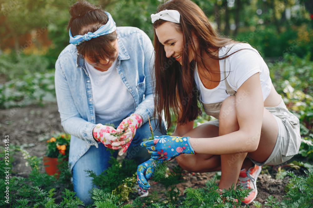 Women works in a garden. Mother with adult daughter near home