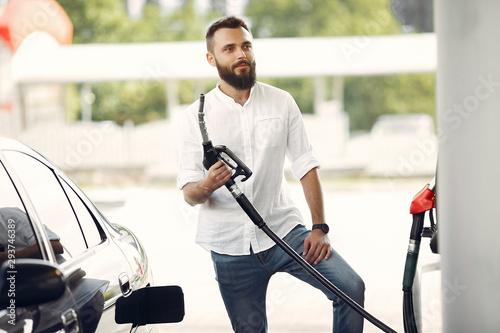 Man on a gas station. Guy refuelong a car. Male in a white shirt.