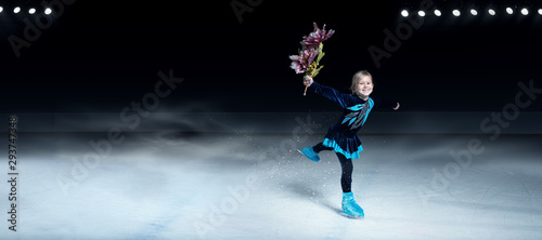 view of child  figure skater on dark ice arena background
