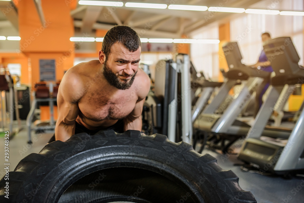 close up photo of a man with beard flipping heavy tire at gym close up photo of a man with beard flipping heavy tire at gym