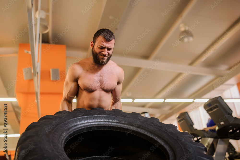 close up photo of a man with beard flipping heavy tire at gym close up photo of a man with beard flipping heavy tire at gym