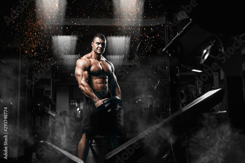 Fotografia Muscular man bodybuilder training in gym and posing