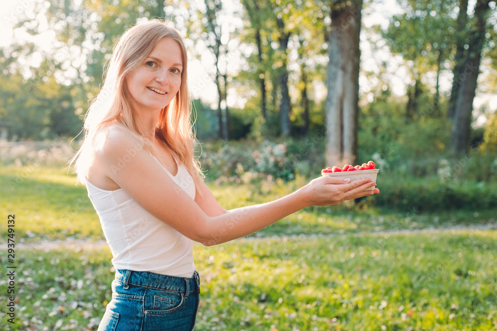 Naklejka premium Woman hold paper box with raspberries. Healthy, organic food concept. Harvest of fruits
