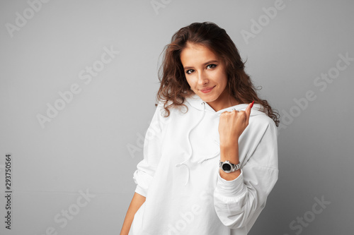 Happy young woman showing victory sign over gray background
