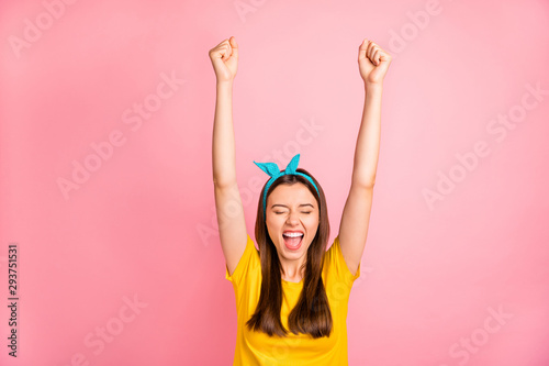 Portrait of thrilled teen with her eyes closed raising fists screaming yeah wearing yellow t-shirt isolated over pink background