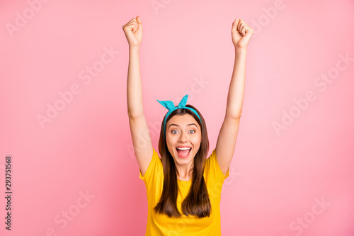 Portrait of impressed lady raising her fists screaming yeah wearing yellow t-shirt isolated over pink background